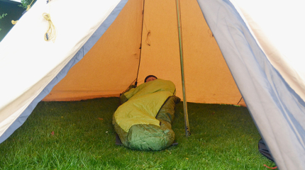 Person i sovepose i telt